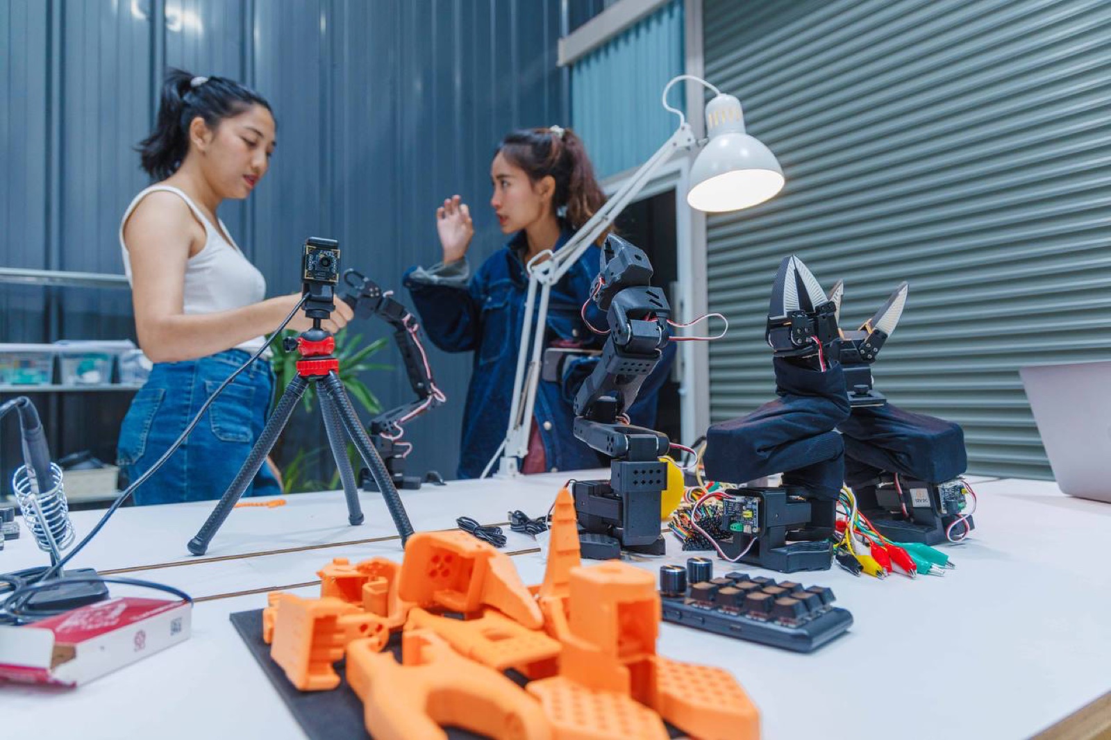 Two engineers assembling robot arms at the Bangkok workshop bench